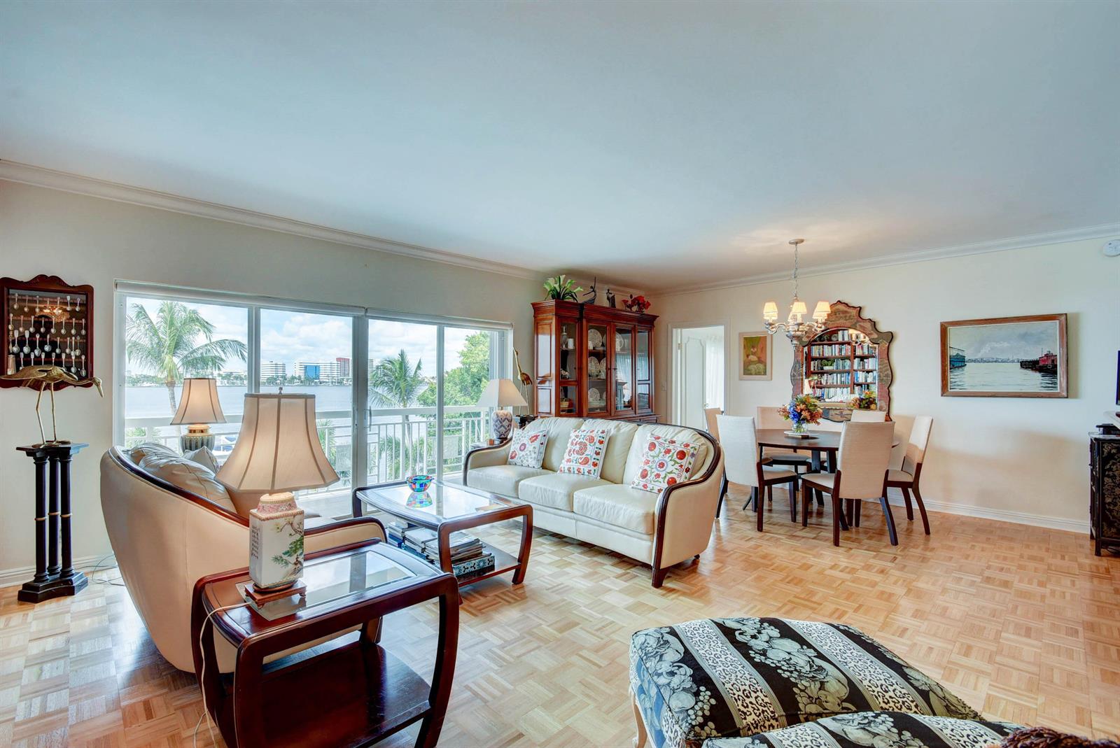 A living and dining room with parquet floors, white leather furniture, and a waterfront balcony view — 250 Bradley Place # 408, Palm Beach FL 33480, PALM BEACH, FL