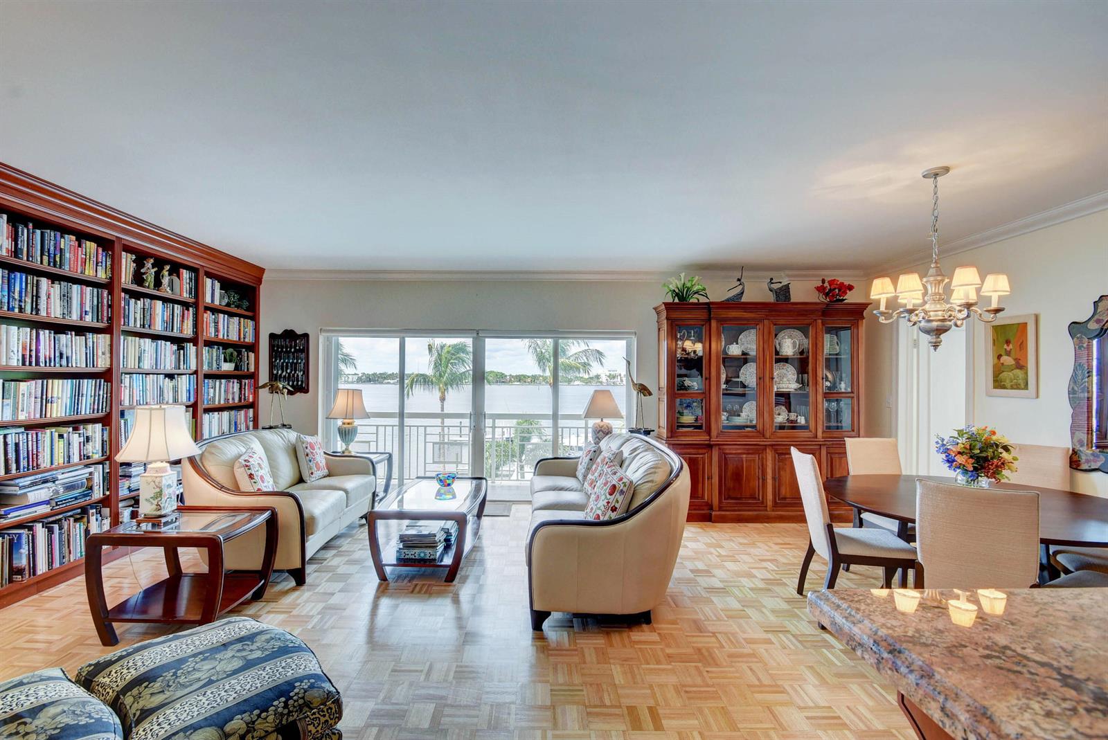 A living and dining room with parquet floors, a large bookcase, and a waterfront balcony — 250 Bradley Place # 408, Palm Beach FL 33480, PALM BEACH, FL