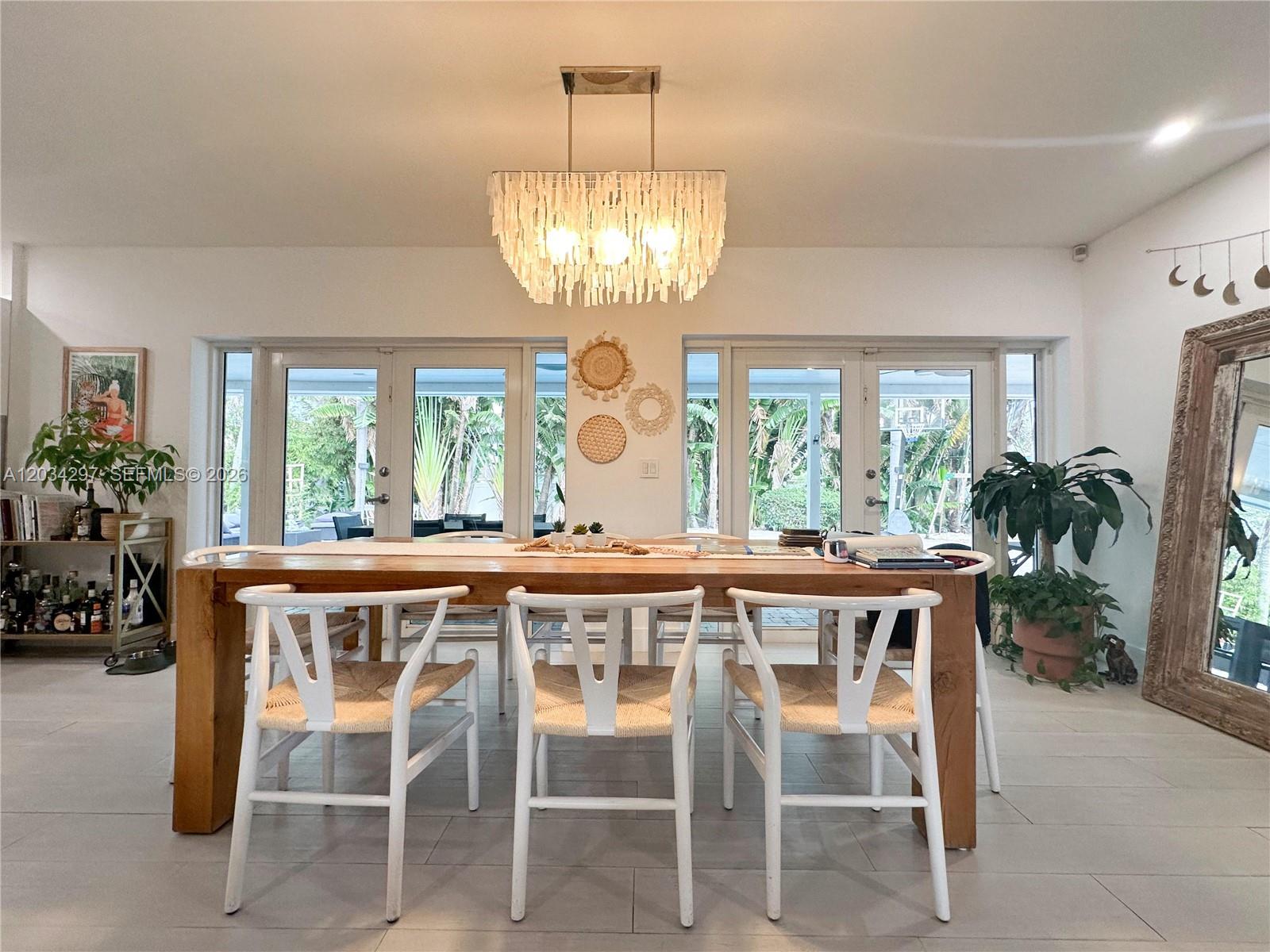 A dining room features a wooden table, white chairs, and a tiered shell chandelier — 20931 NE 24th Ave, Miami FL 33180, MIAMI, FL