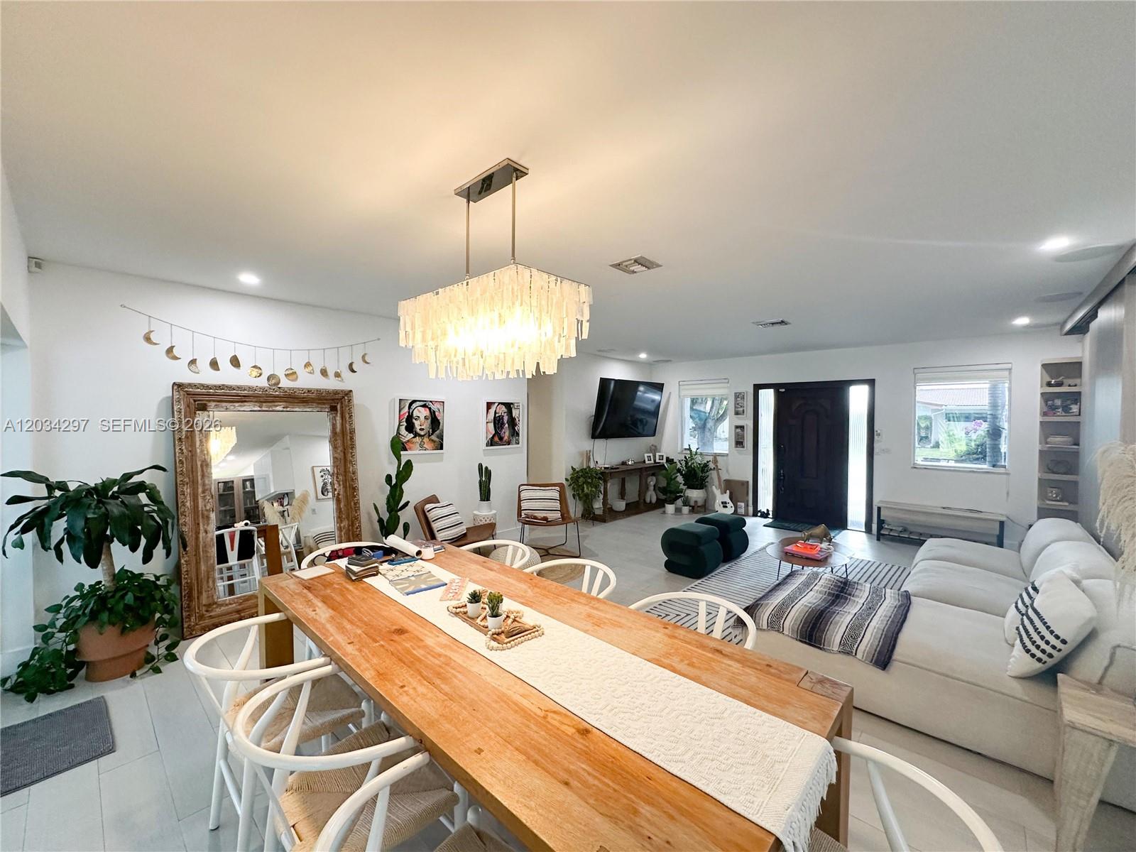 A dining area with a wooden table and chandelier opens into a living room — 20931 NE 24th Ave, Miami FL 33180, MIAMI, FL