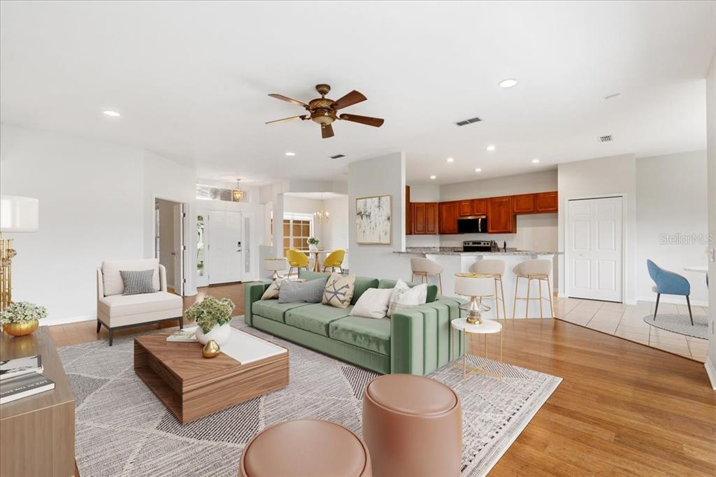 A living room with a green sofa, wooden coffee table, and an open-concept kitchen — 3533 SOMERSET CIRCLE, KISSIMMEE, FL