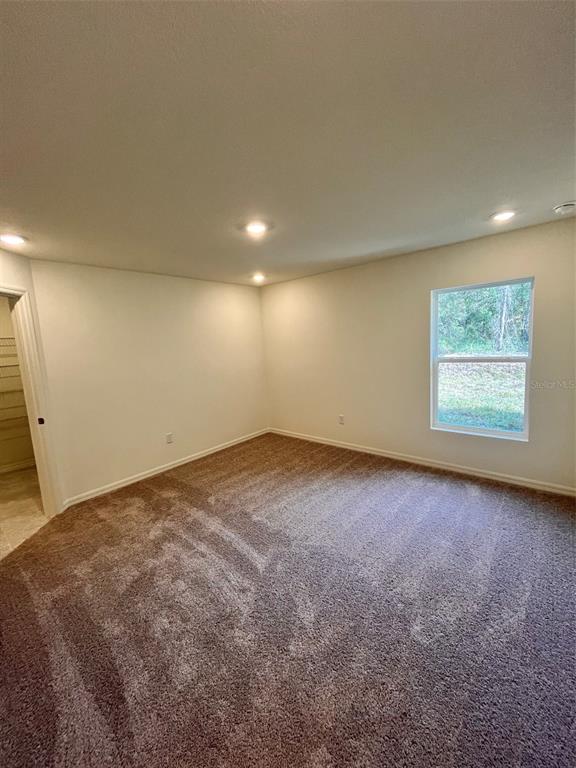 An empty bedroom with beige carpet, white walls, recessed lighting, and a single window — 10150 ISAACSON AVENUE, HASTINGS, FL