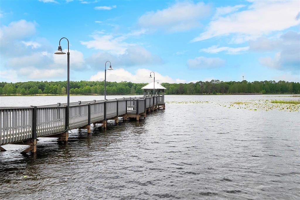 A long wooden pier with a gazebo extends into a calm lake under a cloudy sky — 3446 SOHO ST UNIT 303, ORLANDO, FL