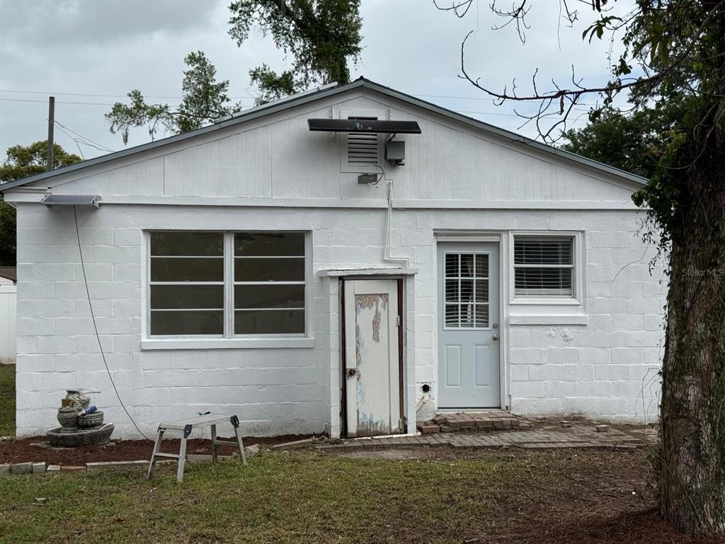 The exterior of a white concrete block house features a window, a door, and a shed — 2014 PAGE AVENUE, ORLANDO, FL