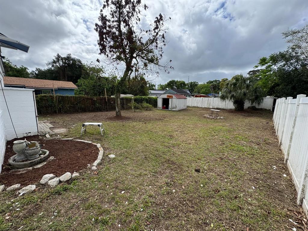 A backyard features a lawn, a storage shed, a large tree, and a white fence — 2014 PAGE AVENUE, ORLANDO, FL