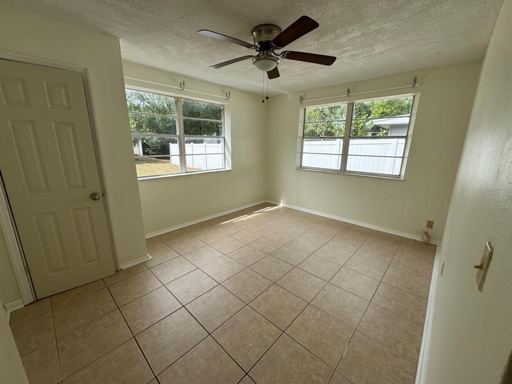 An empty room features light-colored tile flooring, a ceiling fan, and two windows — 2014 PAGE AVENUE, ORLANDO, FL