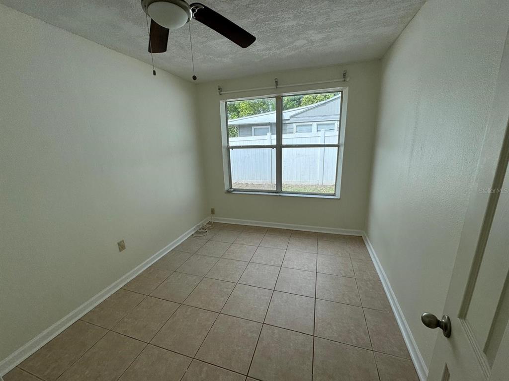 An empty room features beige tile flooring, a ceiling fan, and a window with blinds — 2014 PAGE AVENUE, ORLANDO, FL