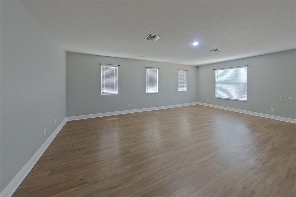 A living room features wood-look flooring, a stone corner fireplace, and a ceiling fan — 30136 JUTLAND COURT, MOUNT DORA, FL