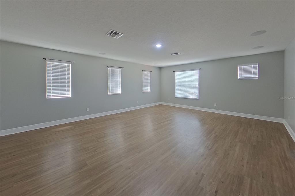 A dining room features wood-look flooring, gray walls, and a central chandelier under a window — 30136 JUTLAND COURT, MOUNT DORA, FL