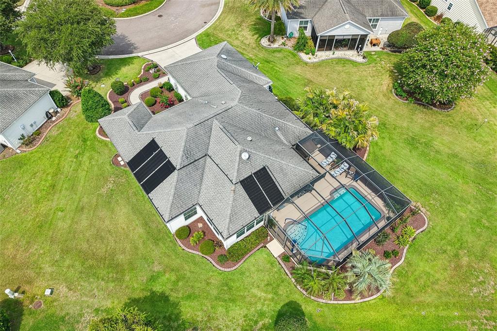 An aerial view of a suburban house with a screened-in pool and rooftop solar panels — 2287 HOPESPRING LOOP, THE VILLAGES, FL