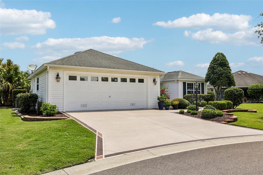 A white house with a two-car garage and a concrete driveway under a blue sky — 2287 HOPESPRING LOOP, THE VILLAGES, FL
