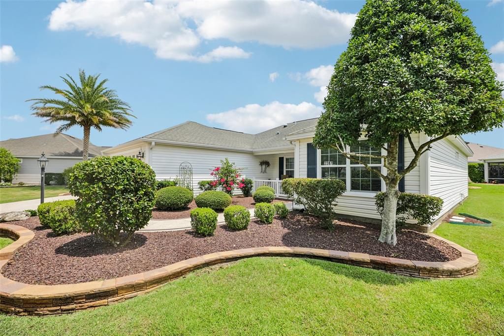A single-story house with white siding, a landscaped front yard, and a curved stone border — 2287 HOPESPRING LOOP, THE VILLAGES, FL
