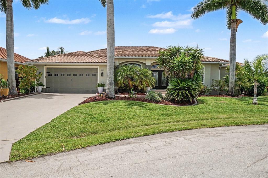 A single-story house with a tile roof, a two-car garage, and palm trees in front — 1442 KIWI COURT, PUNTA GORDA, FL