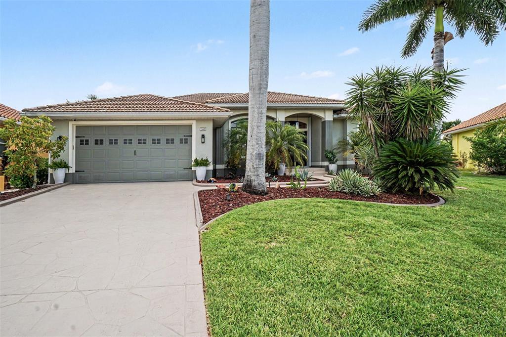 A single-story house with a gray garage, a palm tree, and a landscaped front yard — 1442 KIWI COURT, PUNTA GORDA, FL