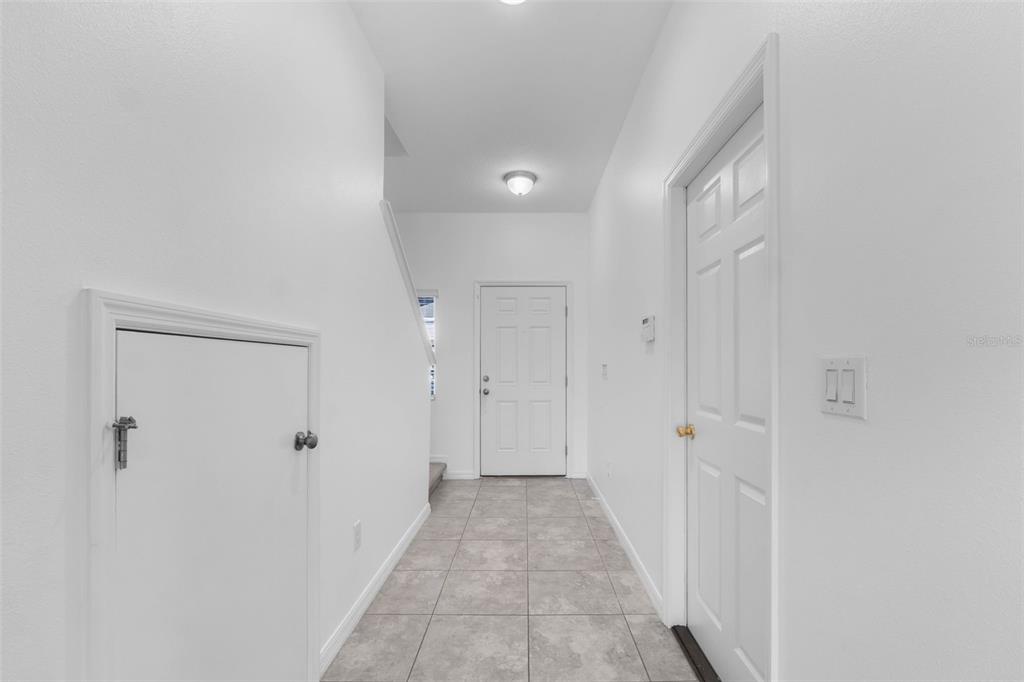 A tiled entryway features a white front door, a staircase, and two white interior doors — 7046 GRAND ELM DRIVE, RIVERVIEW, FL