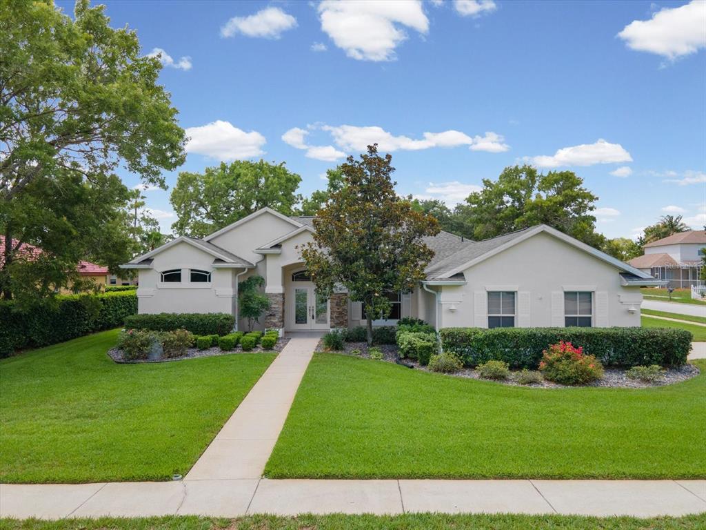 A single-story house with a light-colored stucco exterior, stone accents, and a manicured lawn — 4054 INDIAN RIVER STREET, SPRING HILL, FL