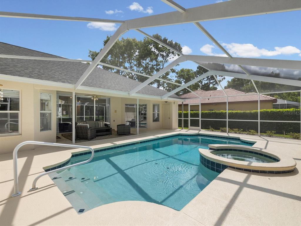 A screened-in swimming pool and spa sit on a patio behind a residential home — 4054 INDIAN RIVER STREET, SPRING HILL, FL