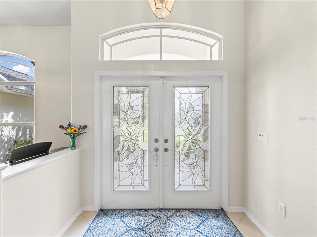 A white double front door with decorative glass panels sits in a bright entryway — 4054 INDIAN RIVER STREET, SPRING HILL, FL