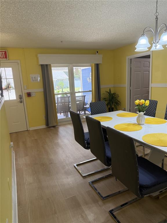 A dining room with yellow walls, a white table, dark chairs, and a sliding glass door — 322 REGAL PARK DRIVE, VALRICO, FL
