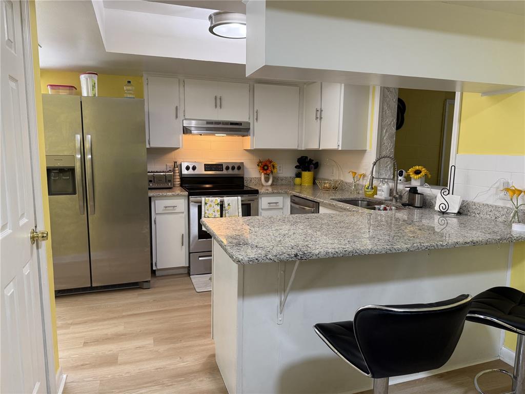 A kitchen features white cabinets, stainless steel appliances, granite countertops, and yellow walls — 322 REGAL PARK DRIVE, VALRICO, FL