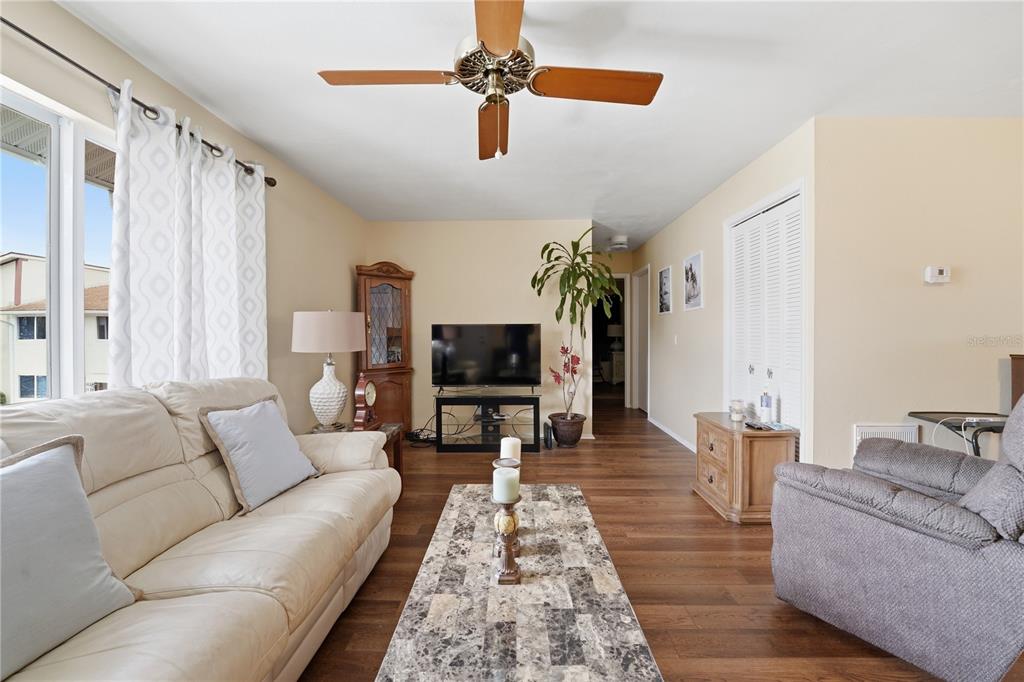 A living room features wood-look flooring, a ceiling fan, a sofa, and a television — 22481 WESTCHESTER BOULEVARD UNIT A3, PUNTA GORDA, FL