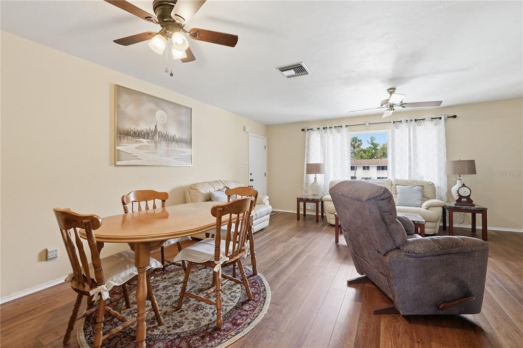 A living and dining room area with wood-look flooring, ceiling fans, and neutral walls — 22481 WESTCHESTER BOULEVARD UNIT A3, PUNTA GORDA, FL