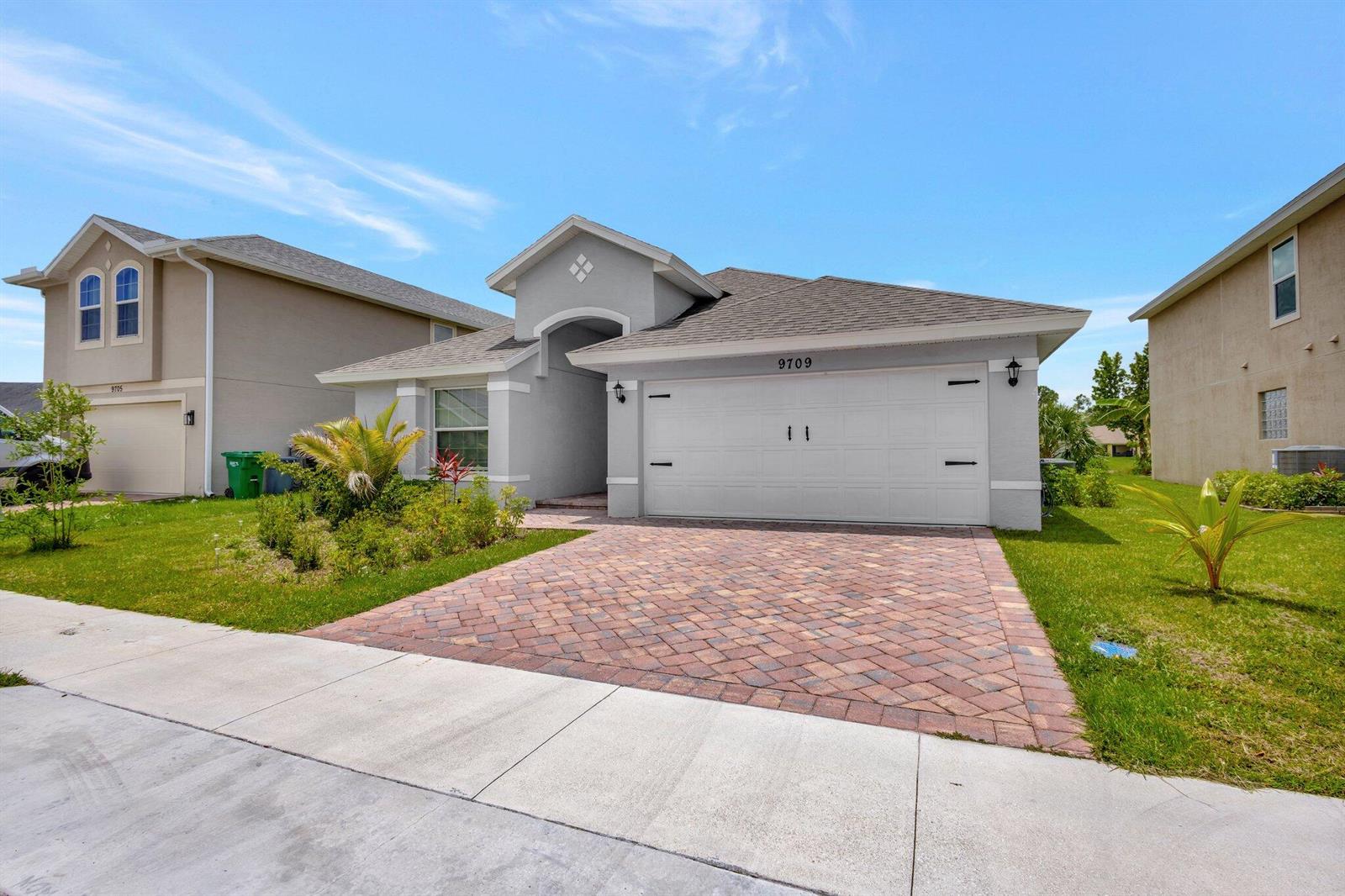 A single-story house with a white garage door and a brick paver driveway — 9709 Starboard Drive, Fort Pierce FL 34945, FORT PIERCE, FL