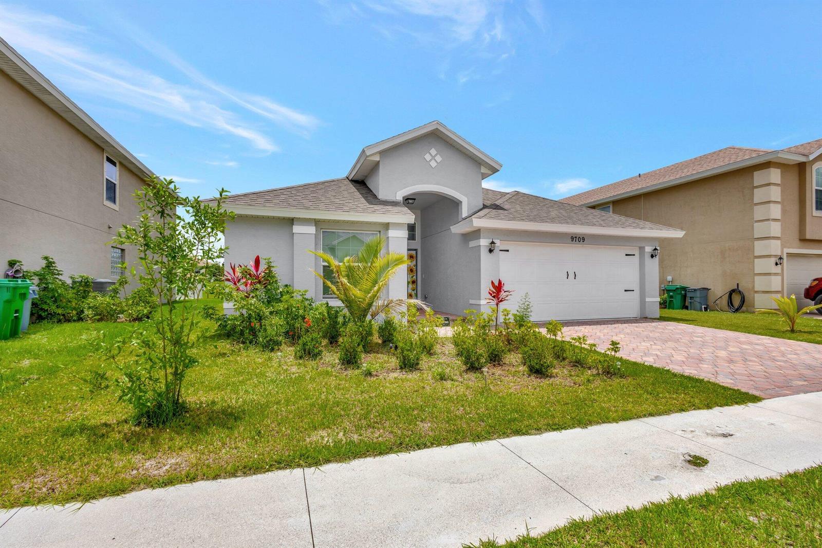A single-story house with a gray stucco exterior, a two-car garage, and a landscaped yard — 9709 Starboard Drive, Fort Pierce FL 34945, FORT PIERCE, FL
