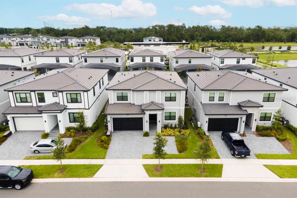 An aerial view shows three modern two-story suburban houses with gray roofs and paved driveways — 5948 HIGH SEAS DRIVE, ORLANDO, FL