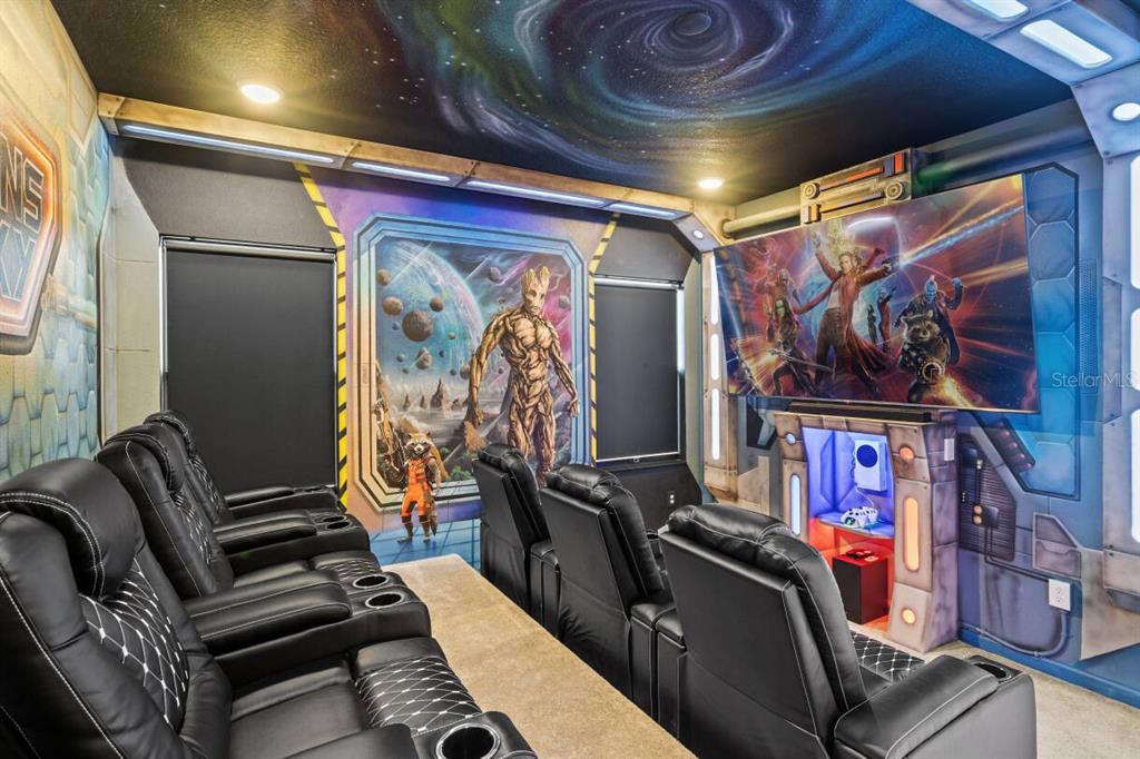A themed home theater features black leather recliners, a large television, and Guardians of the Galaxy-inspired murals — 5948 HIGH SEAS DRIVE, ORLANDO, FL