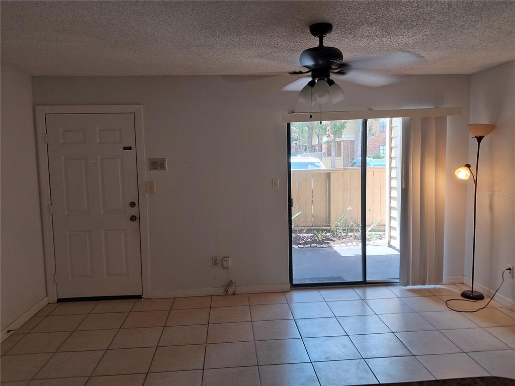 A room with tile flooring, a ceiling fan, a front door, and sliding glass doors — 8648 MALLARD RESERVE DRIVE UNIT 102, TAMPA, FL
