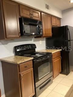 A kitchen features wood cabinets, black appliances, and a speckled countertop — 8648 MALLARD RESERVE DRIVE UNIT 102, TAMPA, FL