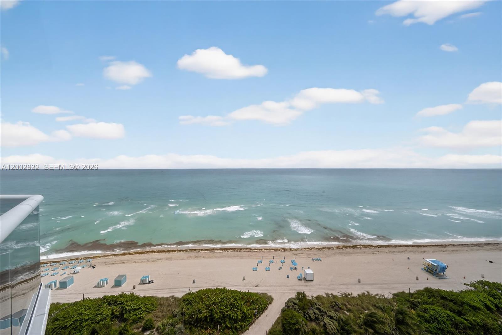 A high-angle view shows a sandy beach, ocean waves, and a blue lifeguard stand — 6767 Collins Ave # 1609, Miami Beach FL 33141, MIAMI BEACH, FL