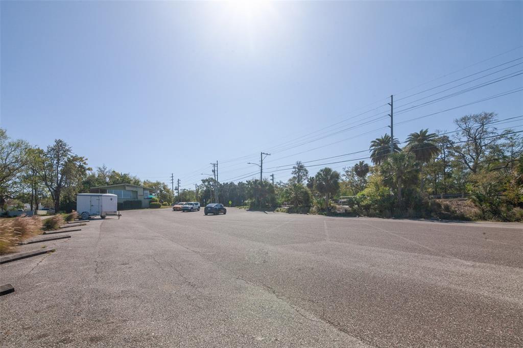 A large, paved parking lot features parking bumpers, a white trailer, and surrounding trees — 1200 8TH AVENUE SW UNIT 1, LARGO, FL