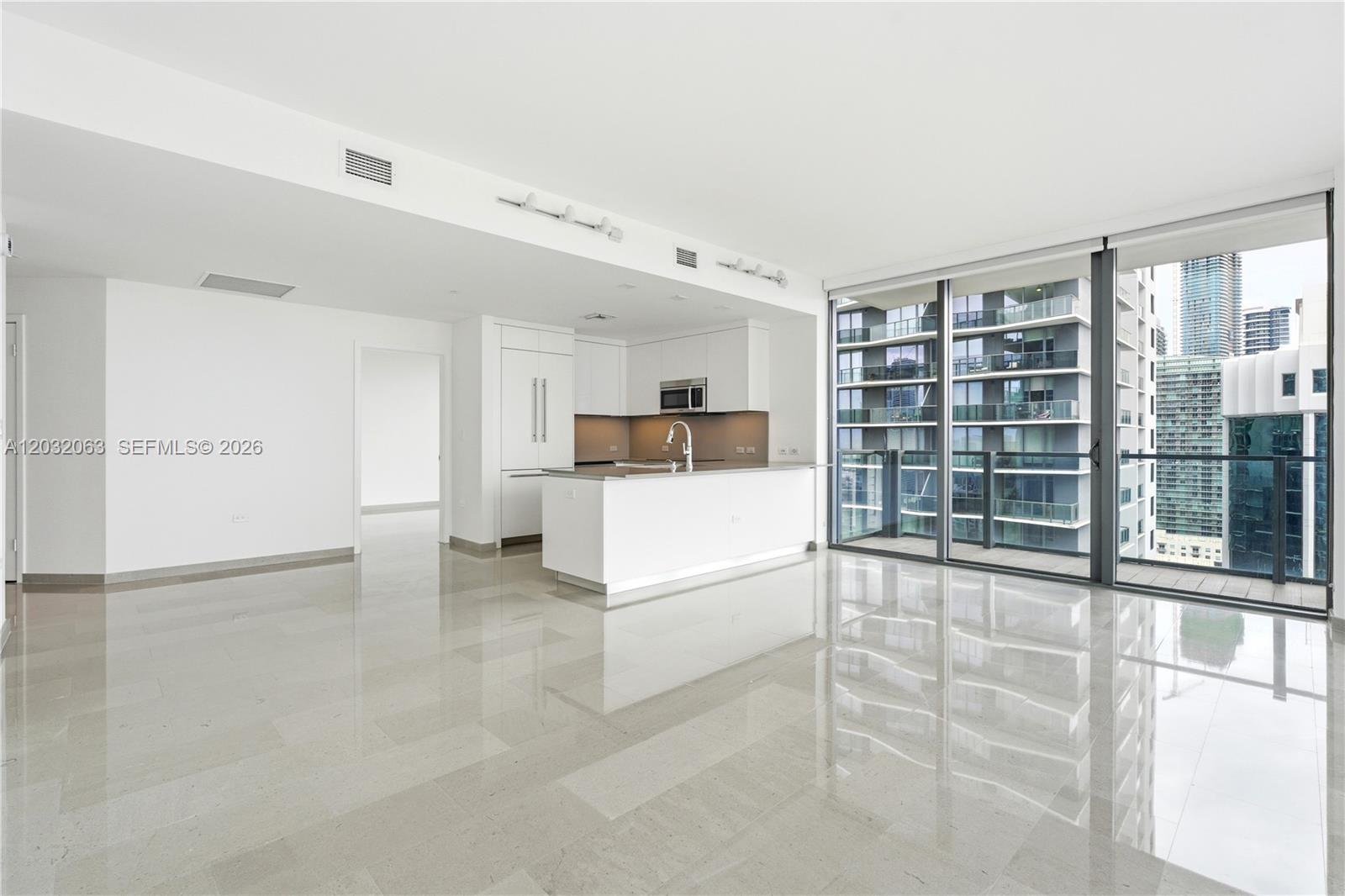 An open-plan kitchen and living area features white cabinetry, polished tile floors, and floor-to-ceiling windows — 88 SW 7th St # 2302, Miami FL 33130, MIAMI, FL