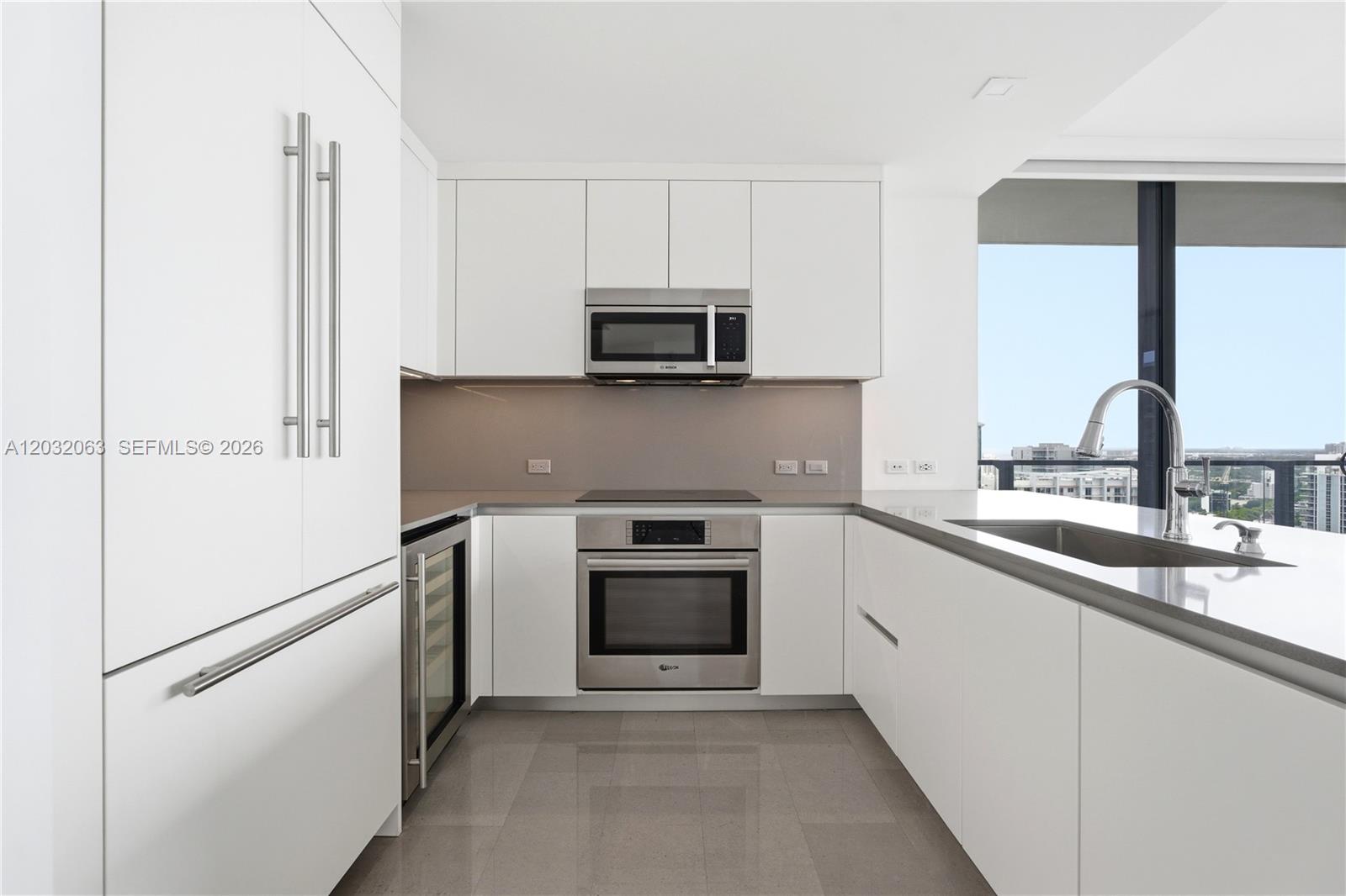 A modern kitchen features white cabinetry, stainless steel appliances, and a view of the city — 88 SW 7th St # 2302, Miami FL 33130, MIAMI, FL