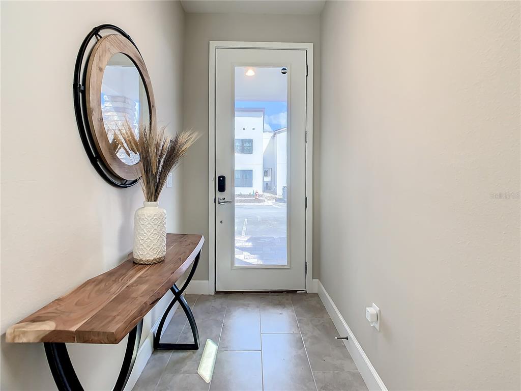A modern entryway features a live-edge console table, a round mirror, and a glass-paneled door — 208 VILLA DOMANI CIRCLE, DAVENPORT, FL