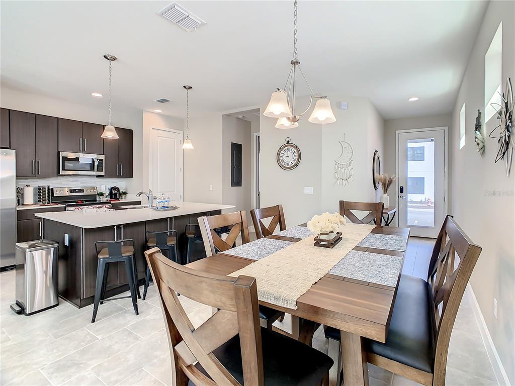 A modern kitchen with dark cabinetry and an island opens into a dining area — 208 VILLA DOMANI CIRCLE, DAVENPORT, FL