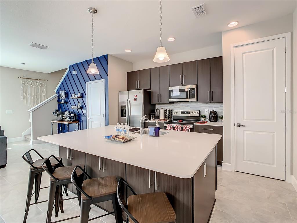 A modern kitchen features a large white island, dark cabinetry, and a blue accent wall — 208 VILLA DOMANI CIRCLE, DAVENPORT, FL