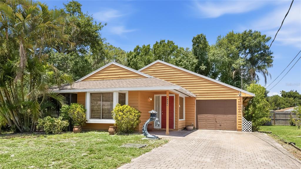 A single-story house with orange horizontal siding, a red front door, and a paved driveway — 4336 CACTUS AVENUE, SARASOTA, FL