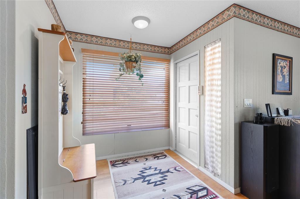 An entryway features a wood-toned coat rack, a window with blinds, and a patterned rug — 4336 CACTUS AVENUE, SARASOTA, FL
