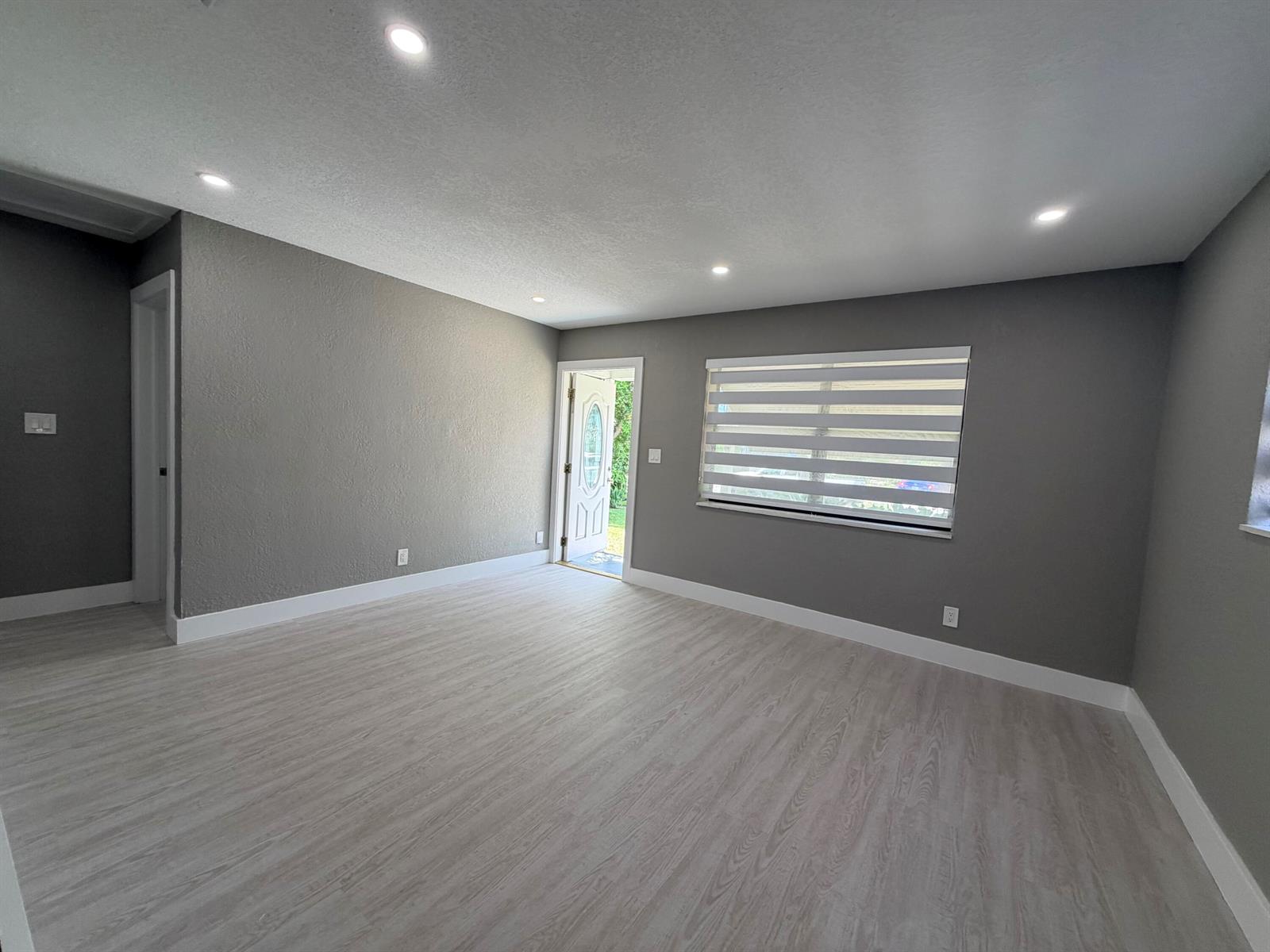 A gray-walled living room features light wood-look flooring, recessed lighting, and a front door — 827 Franklin Road, West Palm Beach FL 33405, WEST PALM BEACH, FL