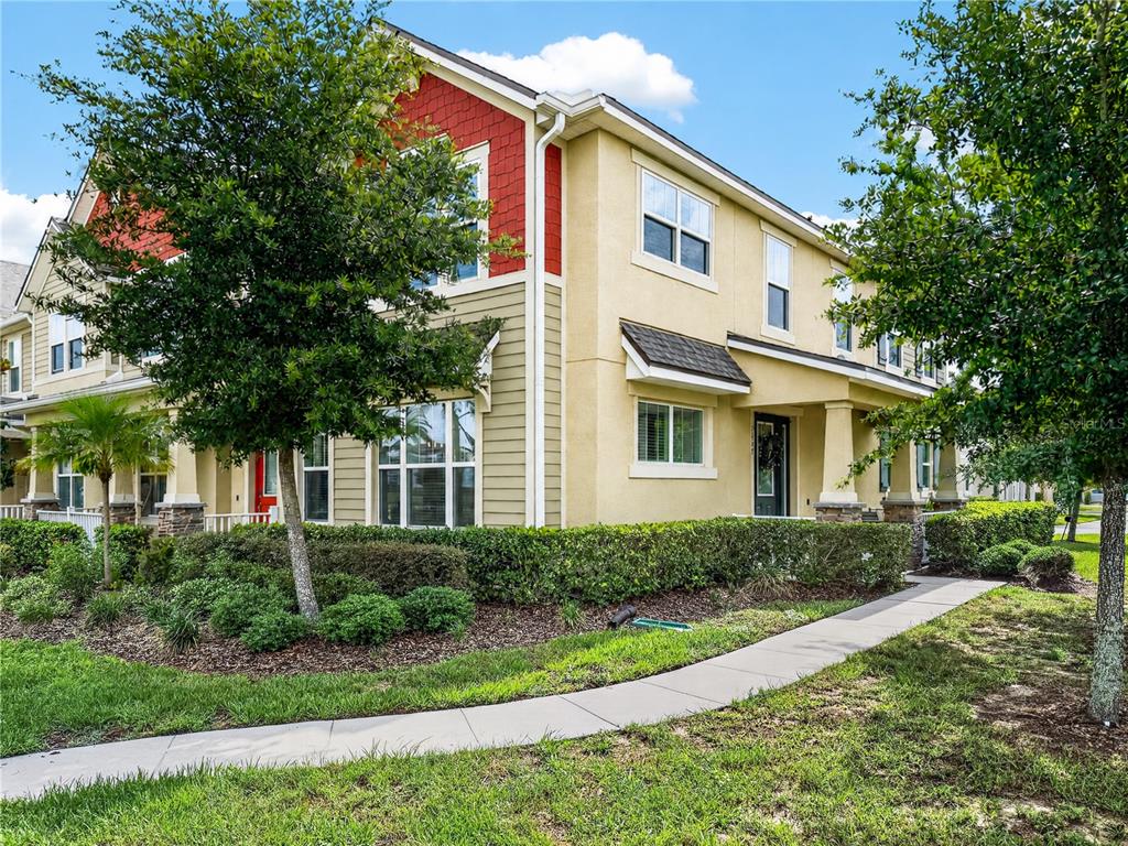 The exterior of a two-story townhouse with tan siding, red shingles, and a front walkway — 9487 RANDAL PARK BOULEVARD, ORLANDO, FL