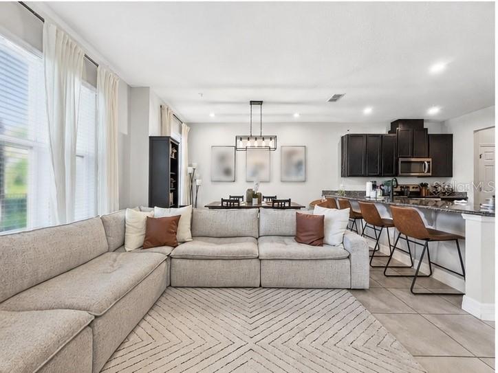 A living room with a large sectional sofa, dining area, and kitchen with bar seating — 9487 RANDAL PARK BOULEVARD, ORLANDO, FL