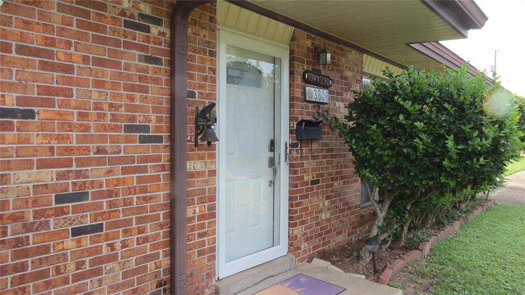 A brick house exterior features a white storm door, a mailbox, and a green bush — 3808 SAN GABRIEL DRIVE, PENSACOLA, FL
