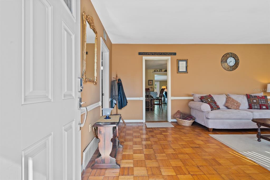 A view from an entryway into a living room with parquet flooring and tan walls — 3808 SAN GABRIEL DRIVE, PENSACOLA, FL