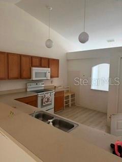 A kitchen features wooden cabinets, a white stove, a double sink, and two pendant lights — 3010 GREYNOLDS AVENUE, SPRING HILL, FL