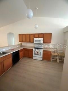 A kitchen features wood cabinets, white appliances, and light-colored wood-look flooring — 3010 GREYNOLDS AVENUE, SPRING HILL, FL