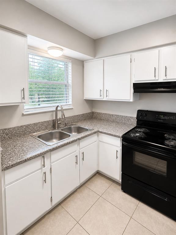 A kitchen features white cabinets, speckled laminate countertops, a double sink, and a black stove — 1179-1179 BENTLEY ROAD UNIT 1, LEESBURG, FL