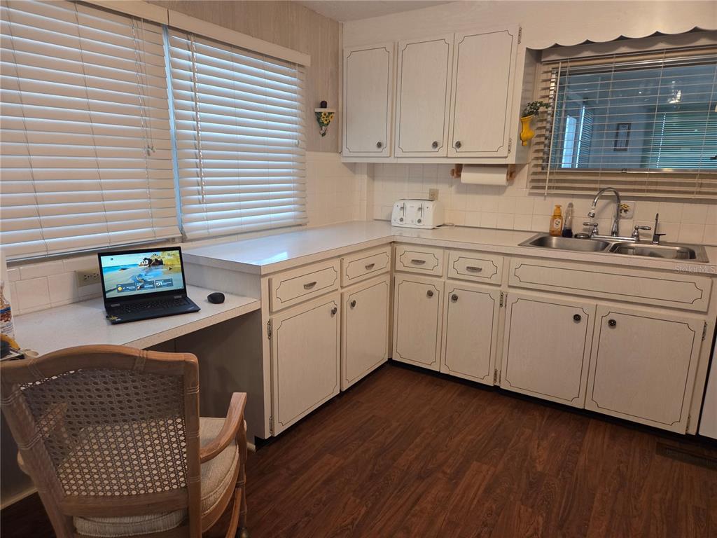 A kitchen with white cabinets, laminate countertops, a laptop desk area, and wood-look flooring — 9900 ULMERTON ROAD UNIT 13, LARGO, FL